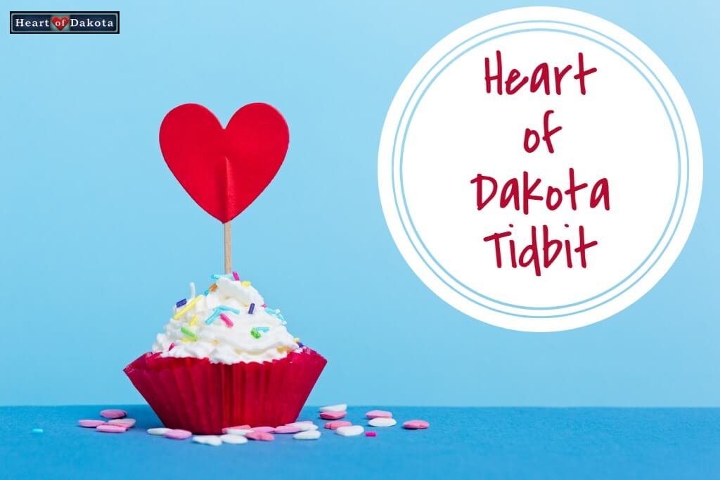 Cupcake with multicolored sprinkles and a paper heart on a toothpick stuck on top. A white circle to the right reads "Heart of Dakota Tidbit."